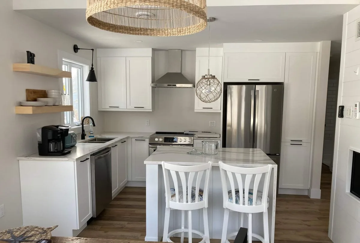 The kitchen with its quartz island, white stools and stainless fridge