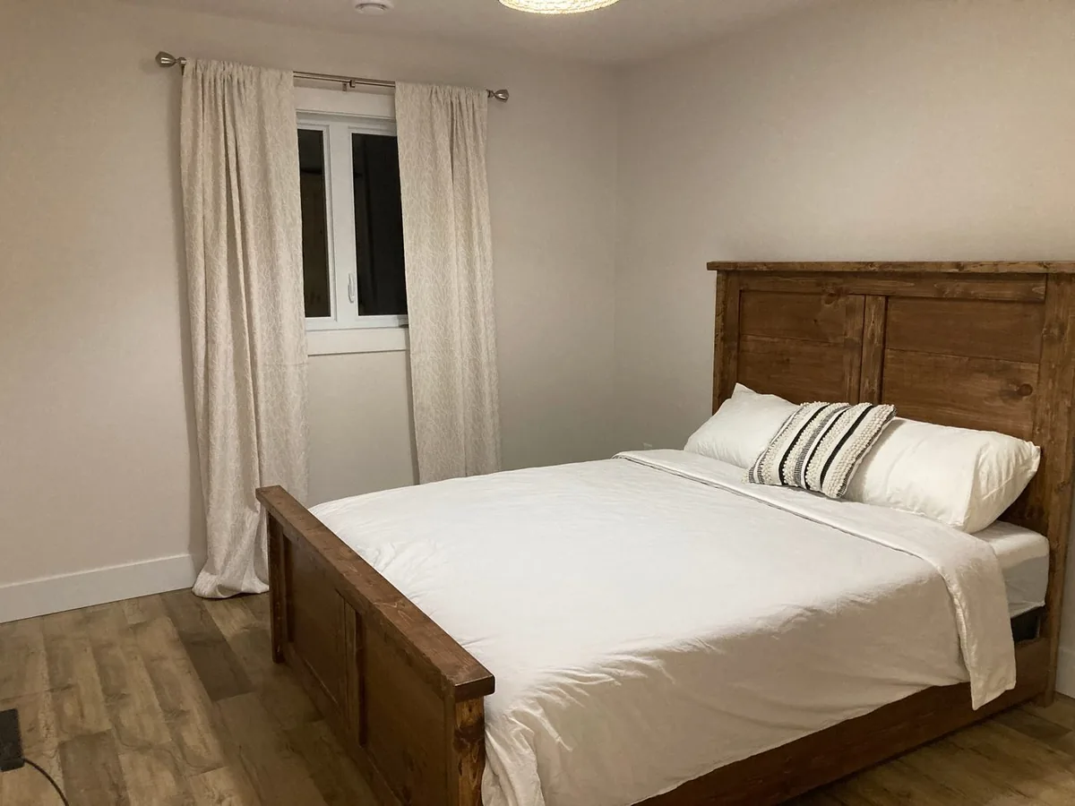 The main-floor queen bedroom with a hand-built wooden bed frame