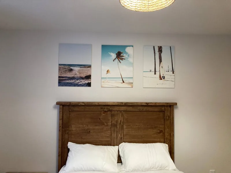 The main-floor queen bed under three beach prints