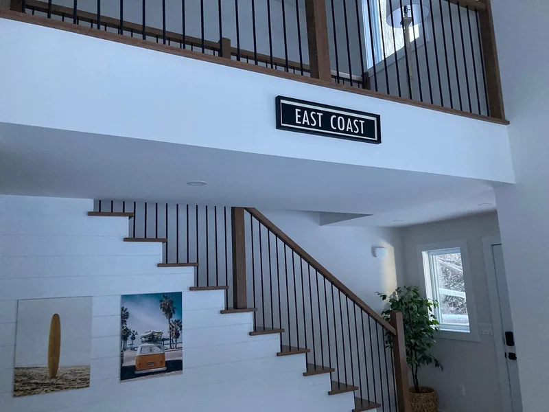The stairs and loft railing with beach prints on the wall