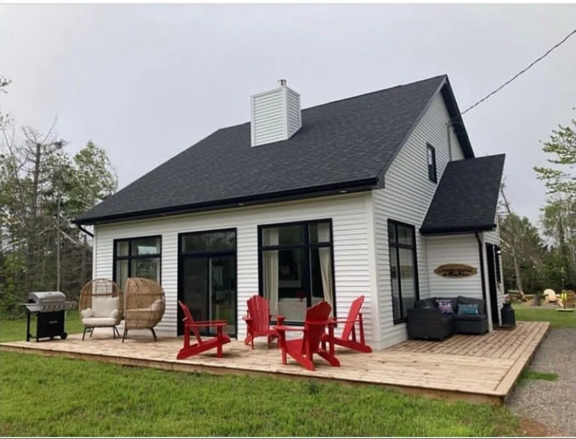 The front deck up close, with red Adirondack chairs, wicker egg chairs and the barbecue
