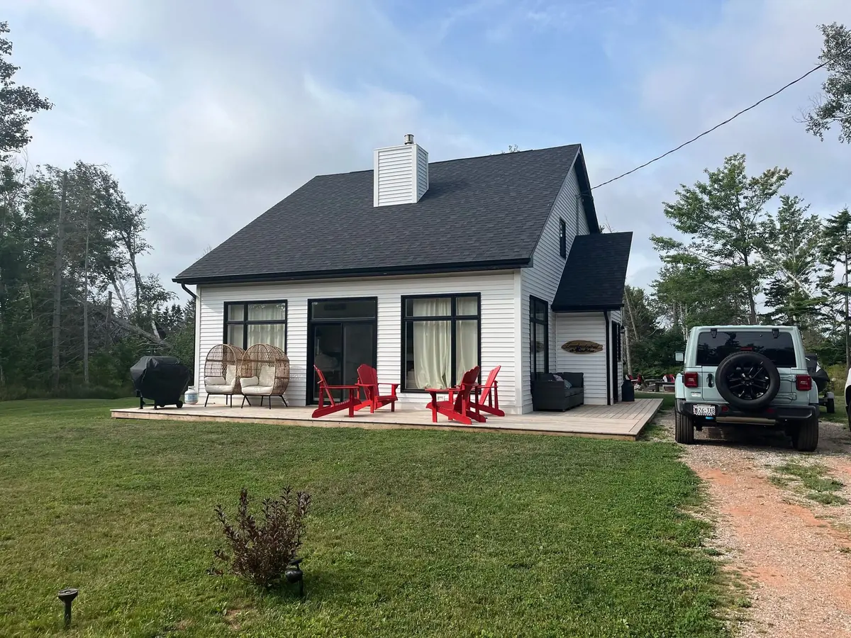The cottage seen from further back, with the red-soil path to the deck and trees all around