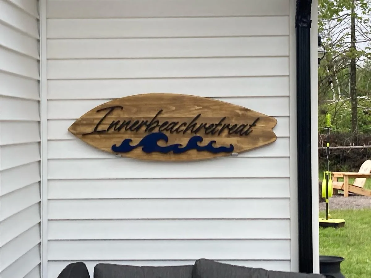 The carved driftwood Innerbeachretreat sign with blue waves, made by Seaside Signs