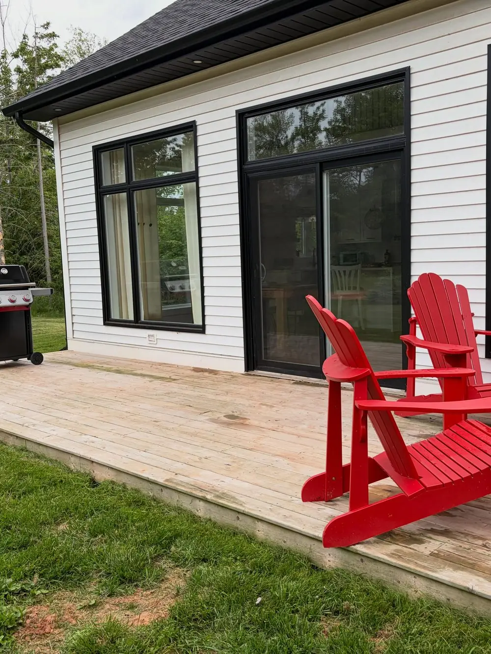 The front deck corner with red Adirondack chairs against black window frames