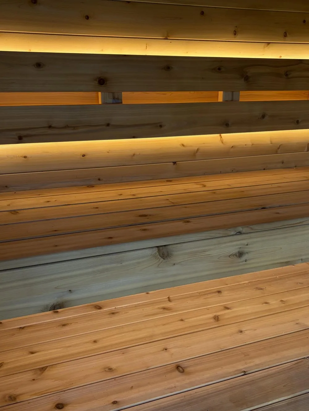 Inside the sauna, cedar benches under warm strip lighting